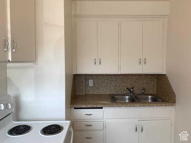 kitchen with a sink, tasteful backsplash, white cabinets, and white range with electric stovetop