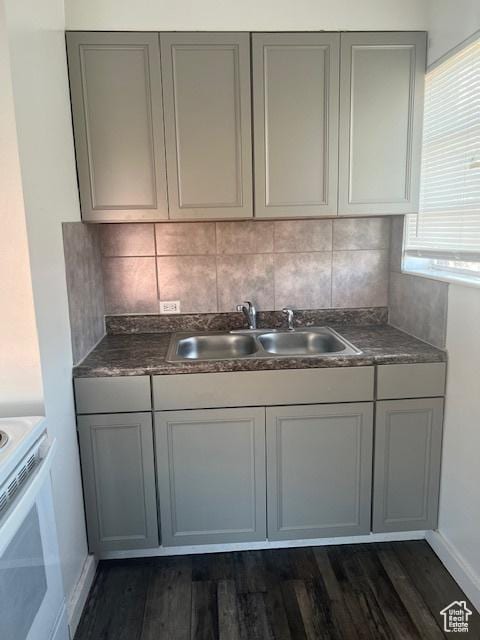 kitchen with dark wood finished floors, gray cabinets, a sink, decorative backsplash, and electric stove