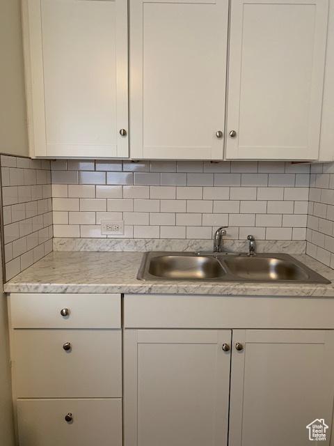 kitchen with a sink, backsplash, light countertops, and white cabinetry