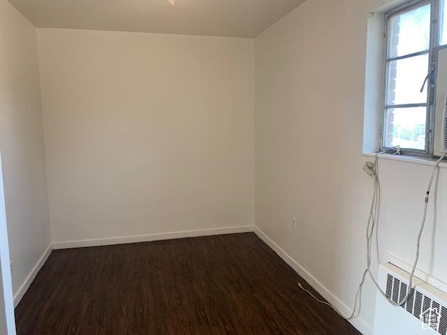 empty room with baseboards and dark wood finished floors