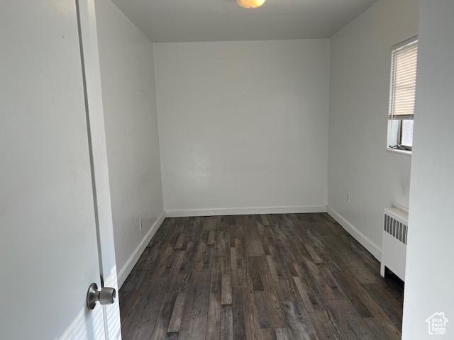 spare room featuring radiator, wood finished floors, and baseboards