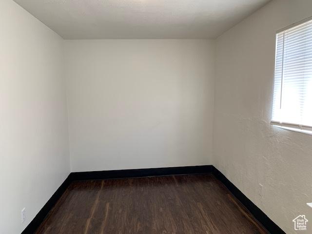 empty room featuring dark wood-type flooring and baseboards