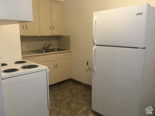 kitchen with white appliances, a sink, decorative backsplash, light countertops, and dark floors
