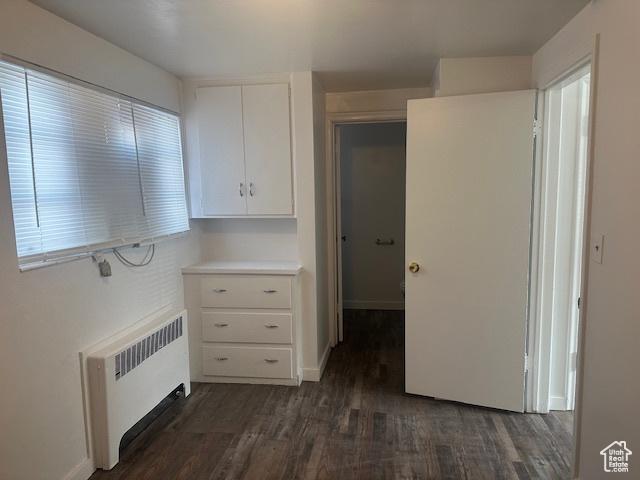 interior space featuring light countertops, white cabinets, radiator, and dark wood-style flooring