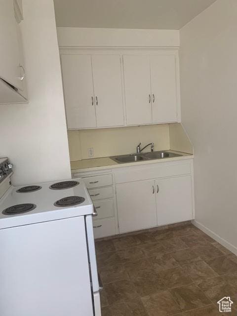 kitchen featuring a sink, electric range, white cabinets, and light countertops
