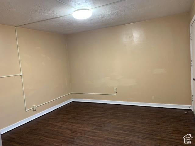 unfurnished room featuring dark wood finished floors, baseboards, and a textured ceiling