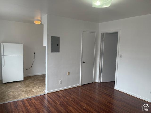 interior space with electric panel, baseboards, and wood finished floors