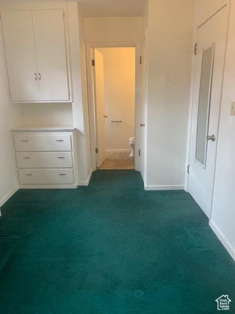 unfurnished bedroom featuring ensuite bath and dark colored carpet