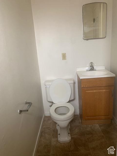 bathroom featuring toilet, vanity, and baseboards