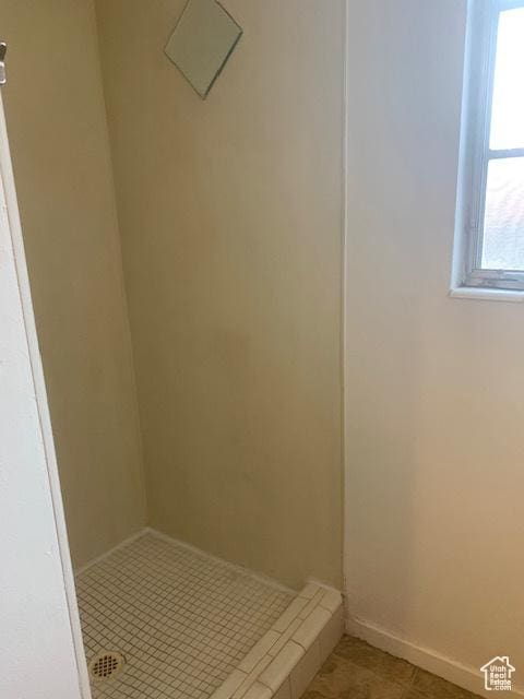 bathroom featuring tile patterned flooring, a shower stall, and baseboards