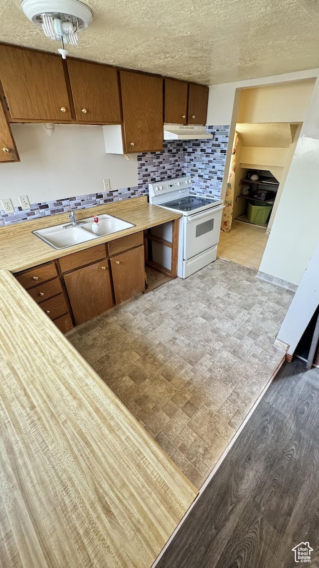 1010 Sullivan Rd, Ogden, UT 84403 - kitchen with backsplash, white range with electric cooktop, under cabinet range hood, light countertops, and a sink