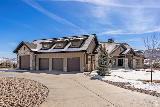 view of front facade featuring a garage, stone siding, board and batten siding, and concrete driveway