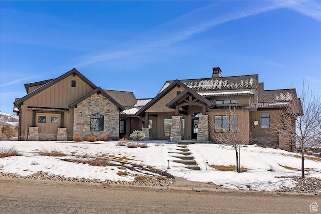 view of front of property featuring stone siding, board and batten siding, and a chimney