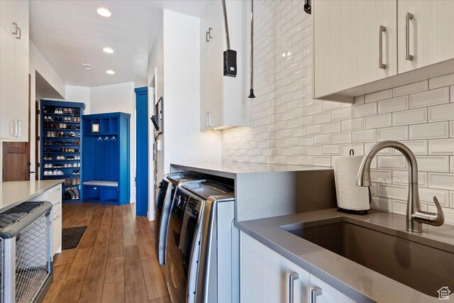 kitchen featuring a sink, backsplash, wood finished floors, heating unit, and separate washer and dryer
