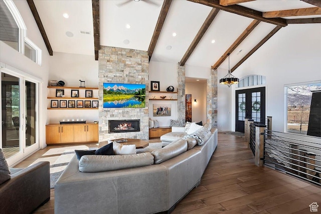 living room featuring wood finished floors, high vaulted ceiling, beam ceiling, a stone fireplace, and french doors