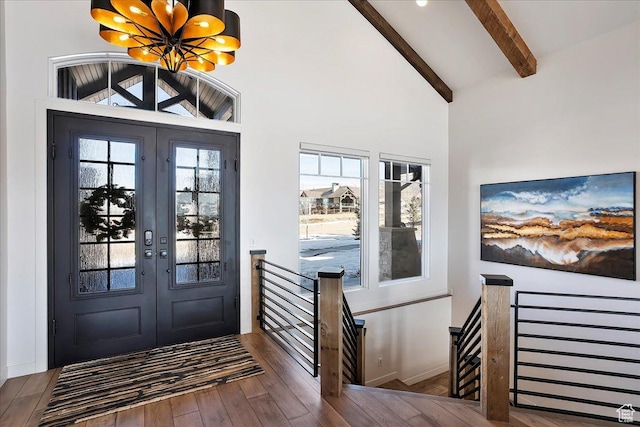 foyer featuring beam ceiling, french doors, an inviting chandelier, and wood finished floors