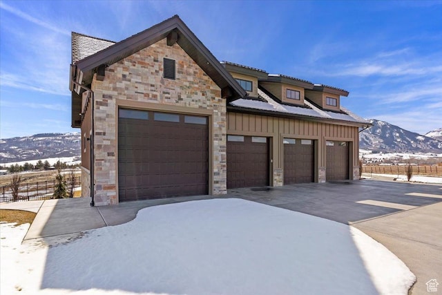 view of front of home with a mountain view, a garage, board and batten siding, and stone siding