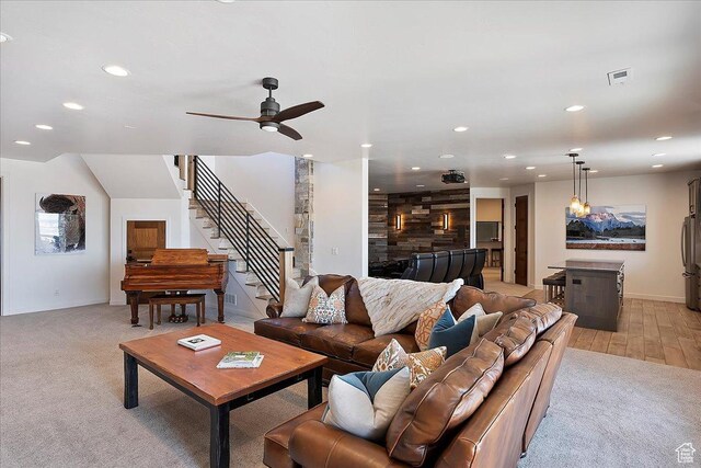 living area with visible vents, recessed lighting, light colored carpet, ceiling fan, and stairs