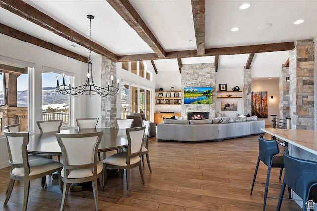 dining space with beamed ceiling, a notable chandelier, hardwood / wood-style flooring, recessed lighting, and a fireplace