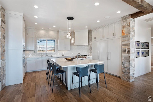 kitchen featuring a kitchen breakfast bar, white cabinets, dark wood-style floors, and tasteful backsplash