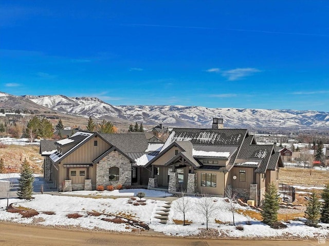 view of front of house featuring a mountain view, stone siding, and a chimney