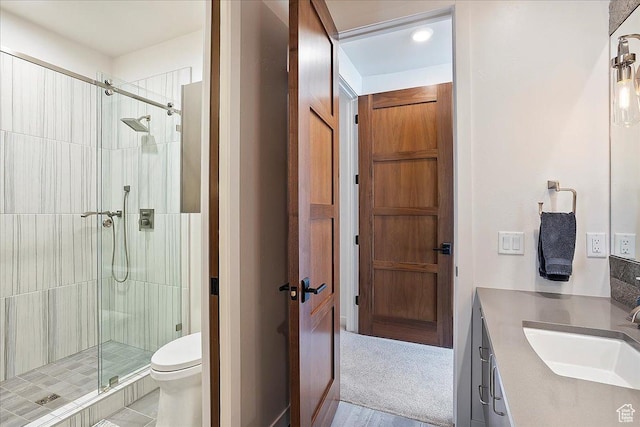 bathroom featuring a stall shower, toilet, and vanity