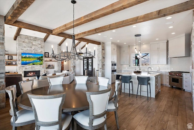 dining area with dark wood finished floors, an inviting chandelier, beamed ceiling, and a fireplace