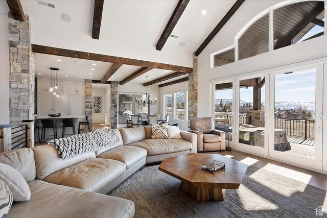 living room with visible vents, beam ceiling, a notable chandelier, high vaulted ceiling, and wood finished floors