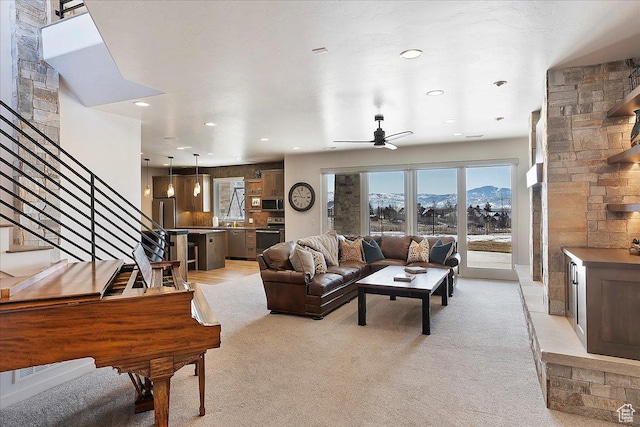 living area with a ceiling fan, recessed lighting, a mountain view, stairway, and light colored carpet