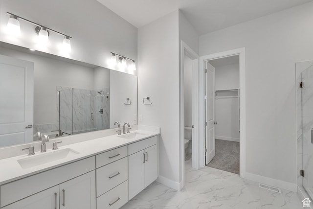 bathroom featuring marble look tiles, a marble finish shower, baseboards, double vanity, and toilet