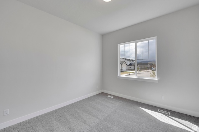 carpeted spare room featuring baseboards
