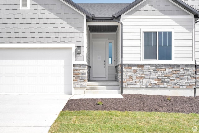 doorway to property with stone siding, concrete driveway, and a garage