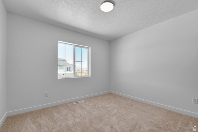 carpeted empty room featuring baseboards, a textured ceiling, and visible vents