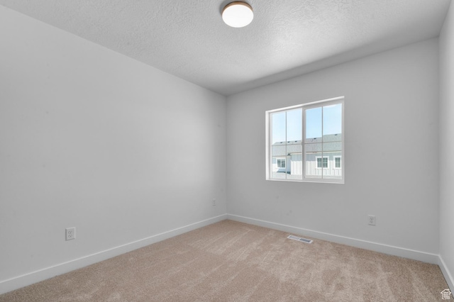 unfurnished room featuring baseboards, a textured ceiling, visible vents, and light carpet