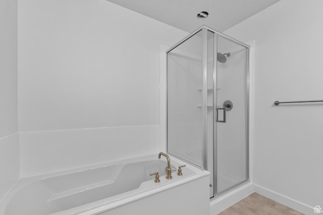 full bath with a stall shower, baseboards, and a bath