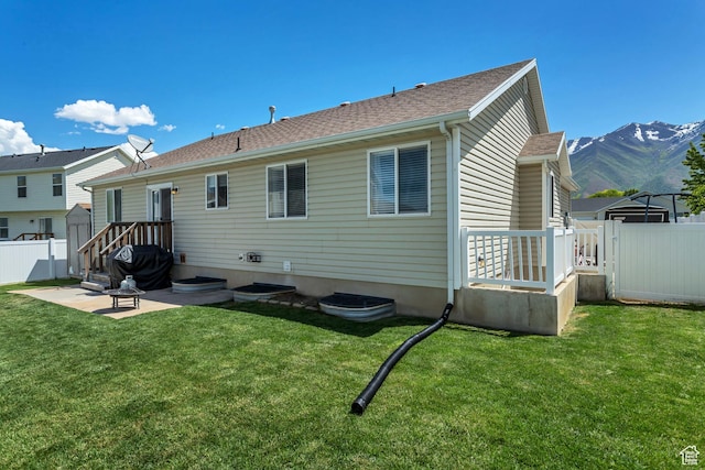 rear view of house with a shingled roof, a yard, a fenced backyard, a patio, and a gate