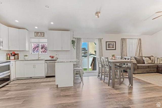 kitchen featuring a wealth of natural light, light wood-style flooring, backsplash, and stainless steel appliances