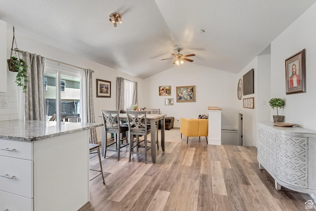 dining area featuring light wood-type flooring, ceiling fan, and vaulted ceiling