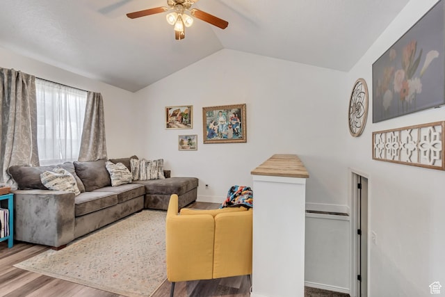living room with a ceiling fan, vaulted ceiling, and wood finished floors