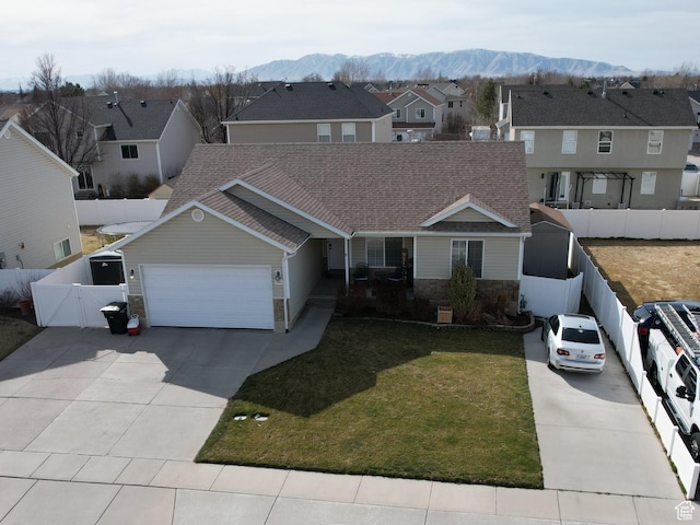 view of front of house with a front lawn, fence, concrete driveway, a garage, and stone siding