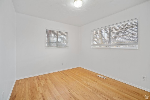 empty room featuring visible vents, baseboards, and wood finished floors