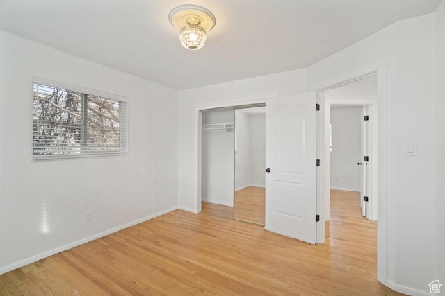 unfurnished bedroom with light wood finished floors, baseboards, and a closet