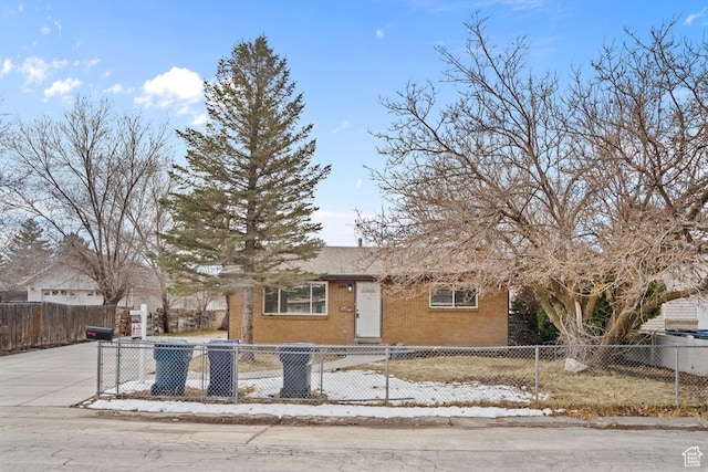 view of front of property with a fenced front yard, brick siding, and driveway