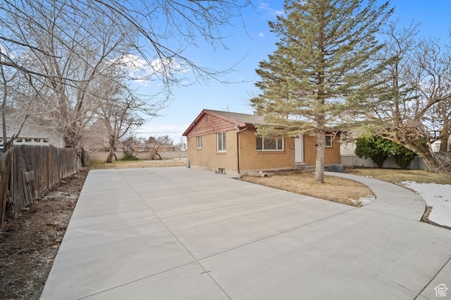 view of side of home with brick siding, driveway, and fence