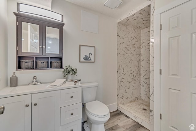 full bath featuring baseboards, toilet, wood finished floors, vanity, and a stall shower