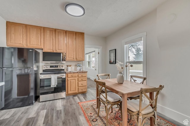 kitchen featuring light countertops, baseboards, light wood-style flooring, light brown cabinets, and appliances with stainless steel finishes