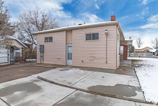 rear view of house featuring a chimney, fence, and a patio