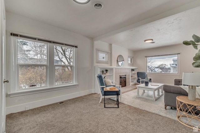 living room featuring baseboards, visible vents, carpet flooring, and a fireplace