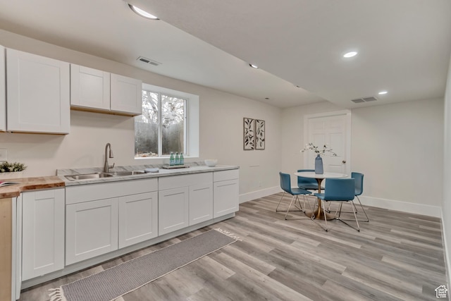 kitchen featuring white cabinets, a sink, and visible vents