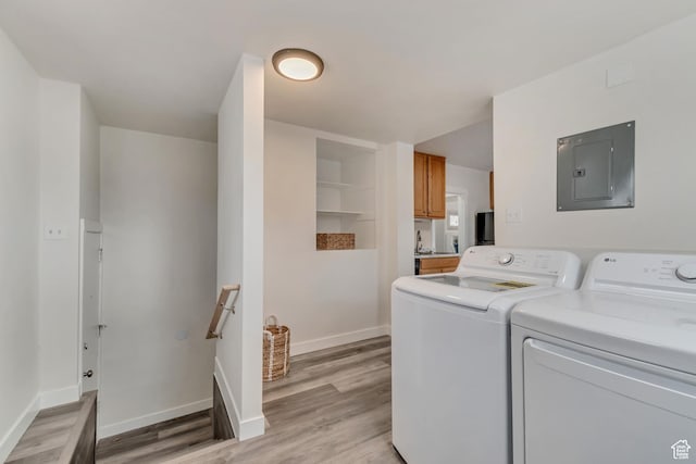 laundry room featuring light wood-style floors, washing machine and clothes dryer, baseboards, and electric panel
